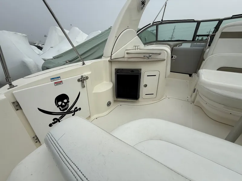 Slide: The Image of 2006 Sea Ray 320 Sundancer boat interior with pirate decal, white seating, and storage compartments. - 14