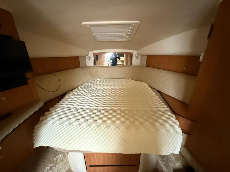 Slide: The Image of 2006 Sea Ray 320 Sundancer cabin interior with bed and wood paneling. - 19