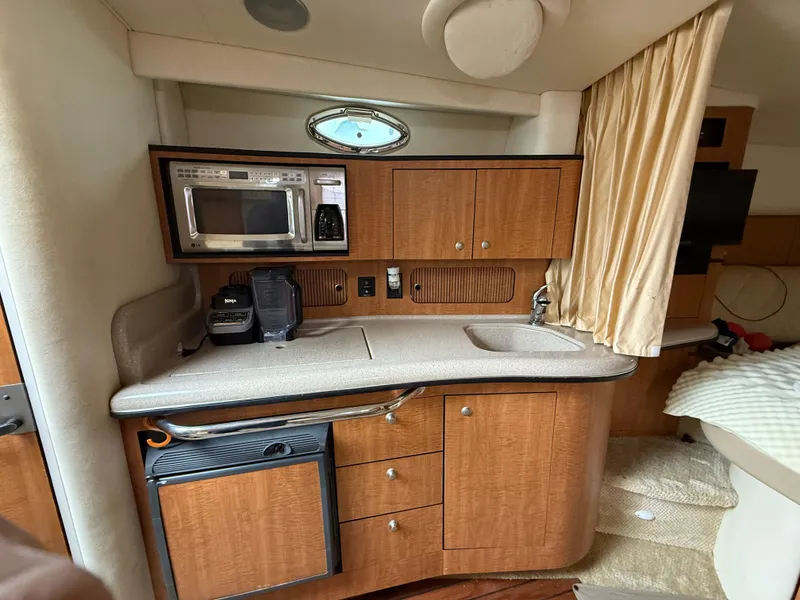 Slide: The Image of 2006 Sea Ray 320 Sundancer interior kitchen with microwave, sink, and wooden cabinetry. - 20