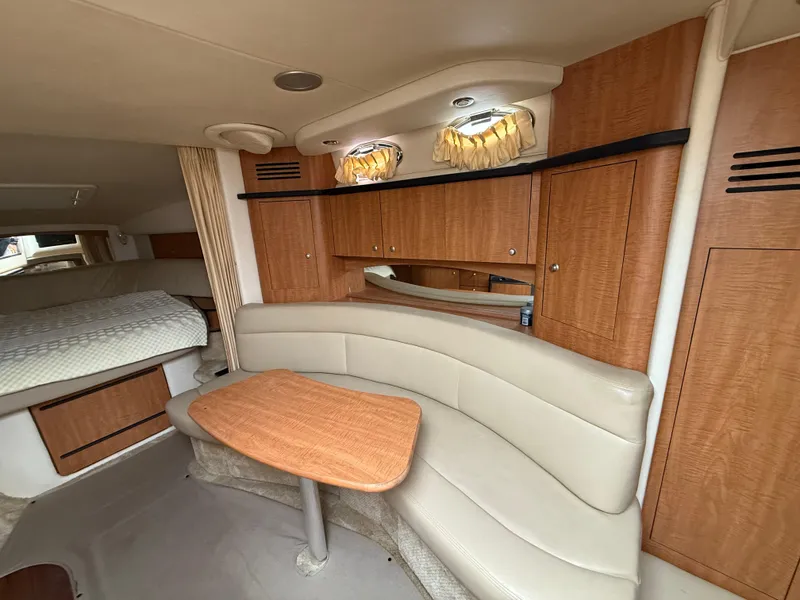 Slide: The Image of 2006 Sea Ray 320 Sundancer cabin interior with beige seating and wooden cabinetry. - 30