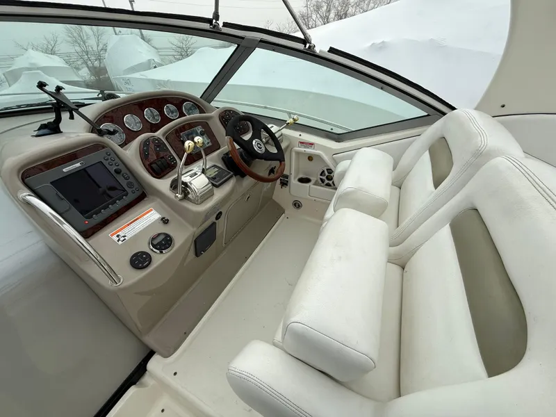 Slide: The Image of 2006 Sea Ray 320 Sundancer helm with white seating and modern controls. - 6