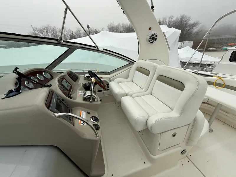 Slide: The Image of 2006 Sea Ray 320 Sundancer helm with dual white seats and control panel. - 7