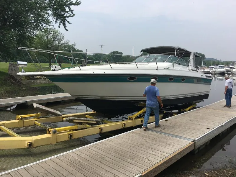 Slide: The Image of 1989 Regal Commodore 360 boat on trailer at dock, two people nearby. - 2