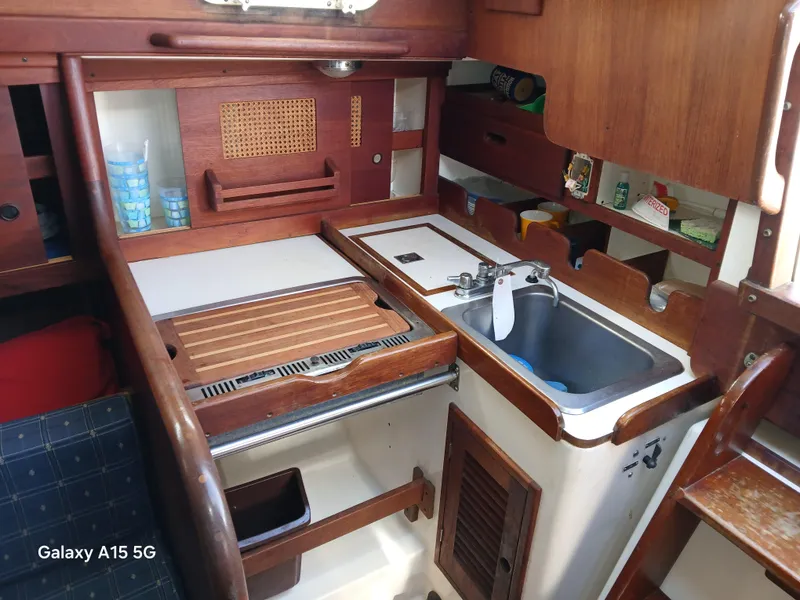 Slide: The Image of 1981 Tartan 33 yacht interior kitchen with sink, wooden cabinetry, and storage shelves. - 2