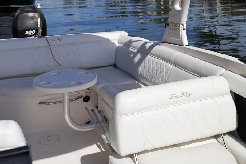 Slide: The Image of 2015 Sea Ray 270 Sundeck Outboard with white seating and table on calm water. - 21