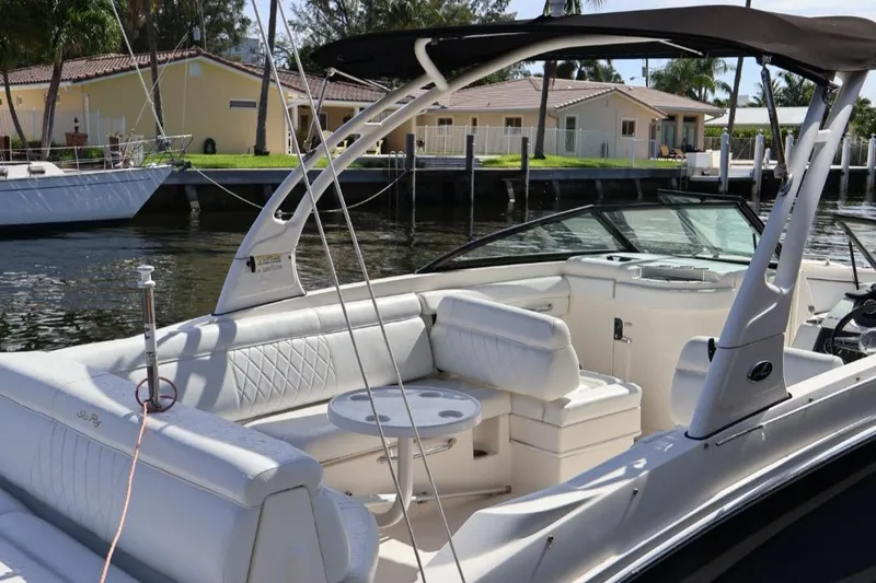 Slide: The Image of 2015 Sea Ray 270 Sundeck Outboard with white seating, docked near waterfront homes. - 23