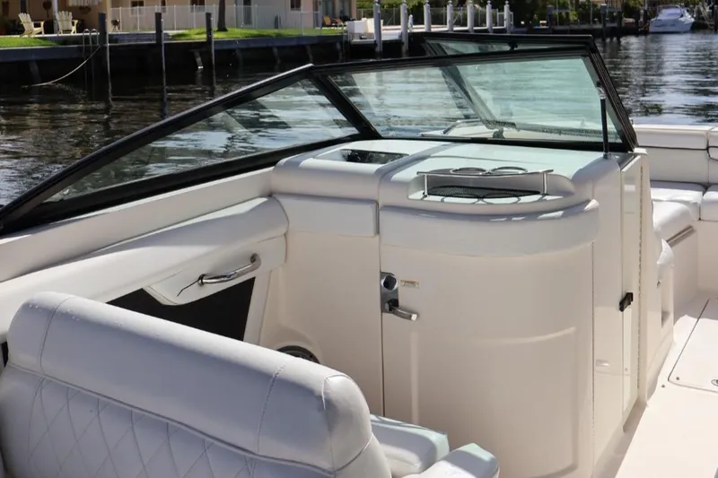 Slide: The Image of 2015 Sea Ray 270 Sundeck Outboard interior with seating and console, docked by the water. - 6