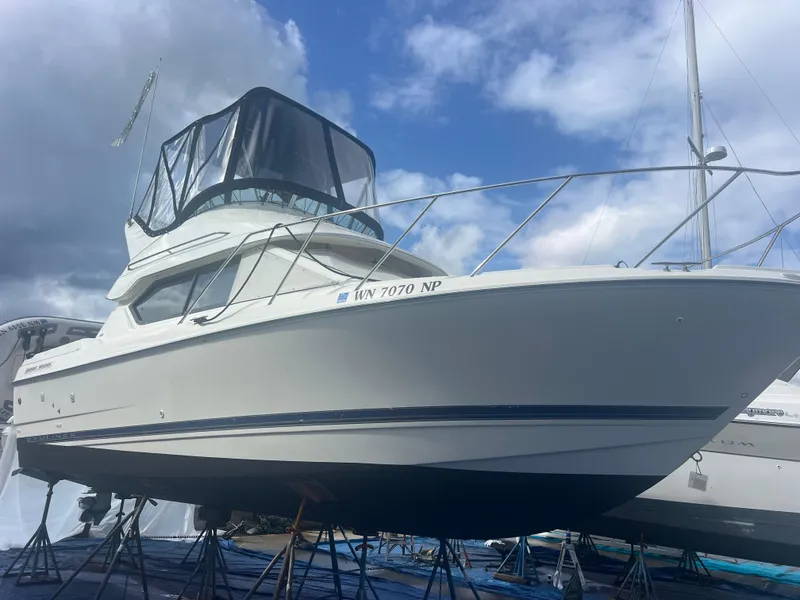 Slide: The Image of 2004 Bayliner 2858 Ciara Classic Command Bridge boat on stands under cloudy sky. - 1