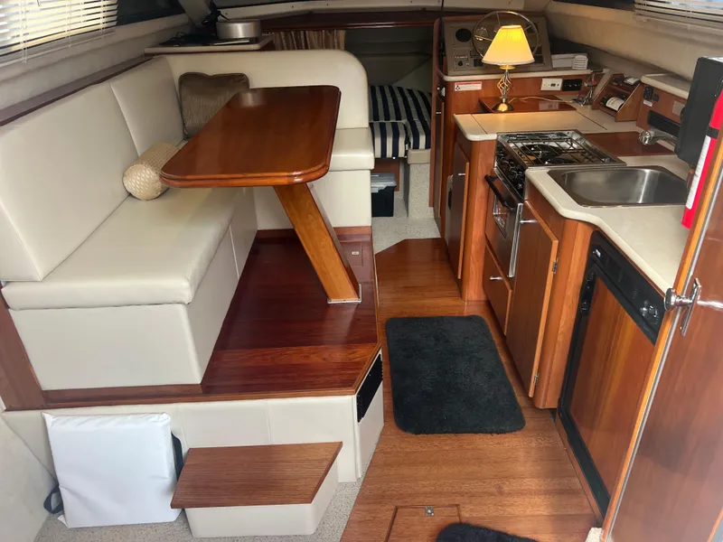 Slide: The Image of 2004 Bayliner 288 Ciara Classic Command Bridge interior with kitchen, dining area, and wood finishes. - 10
