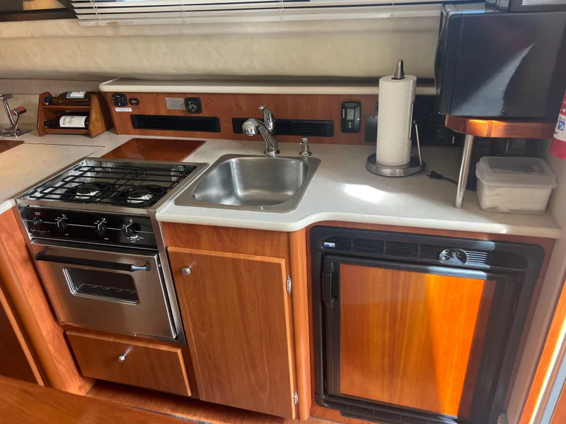 Slide: The Image of 2004 Bayliner 288 Ciara Classic Command Bridge kitchen with stove, sink, and fridge. - 12