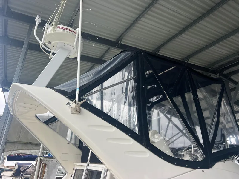 Slide: The Image of 2004 Bayliner 288 Ciara Classic Command Bridge under a metal roof, featuring a clear enclosure. - 34