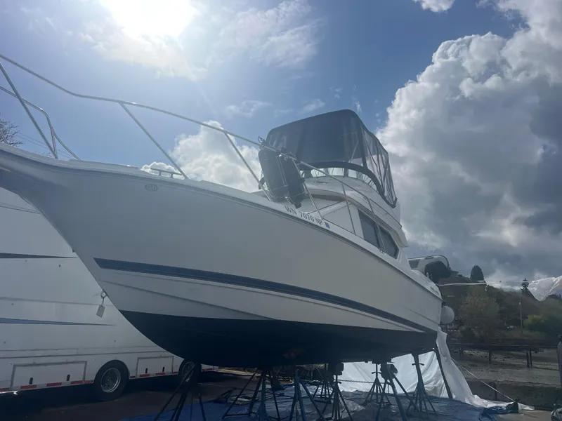Slide: The Image of 2004 Bayliner 2858 Ciara Classic Command Bridge on stands under cloudy sky. - 4