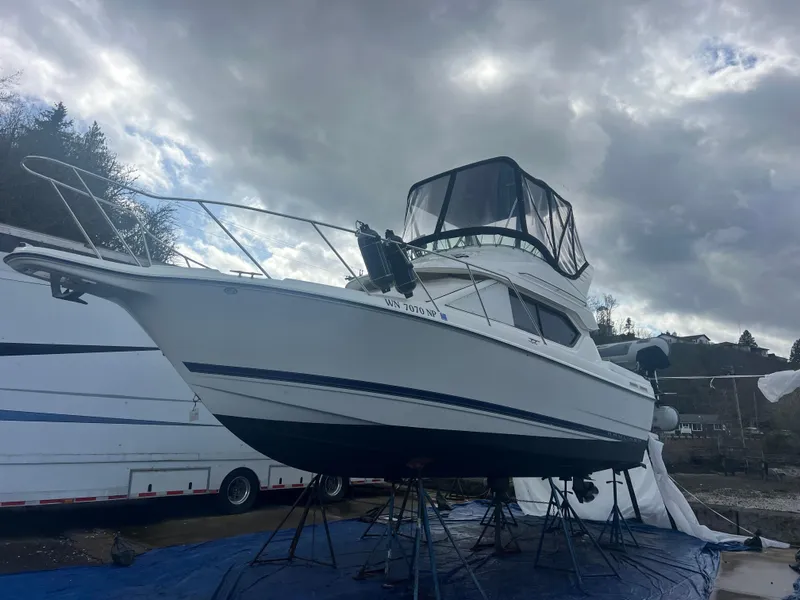 Slide: The Image of 2004 Bayliner 2858 Ciara Classic Command Bridge boat on stands under cloudy sky. - 5
