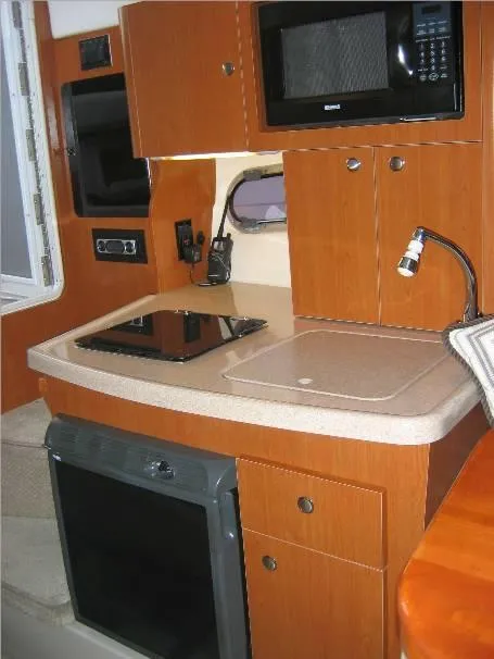Slide: The Image of 2003 Four Winns 268 Vista boat kitchen with microwave, stove, and sink. - 10