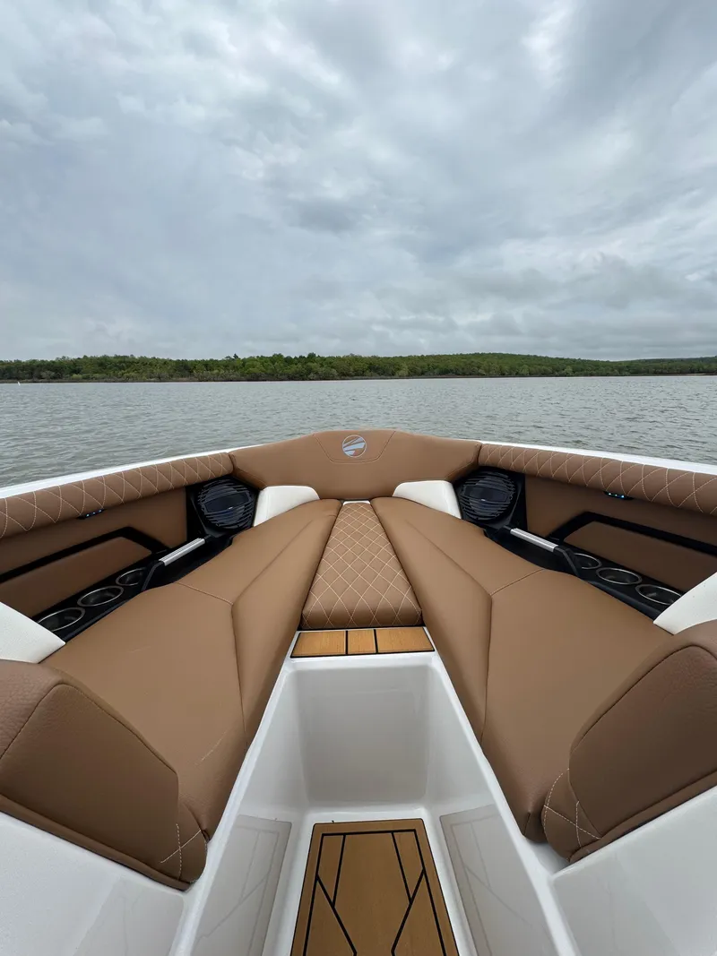 Slide: The Image of 2025 Tigé Z5 boat interior with brown seating, on a calm lake under cloudy skies. - 10