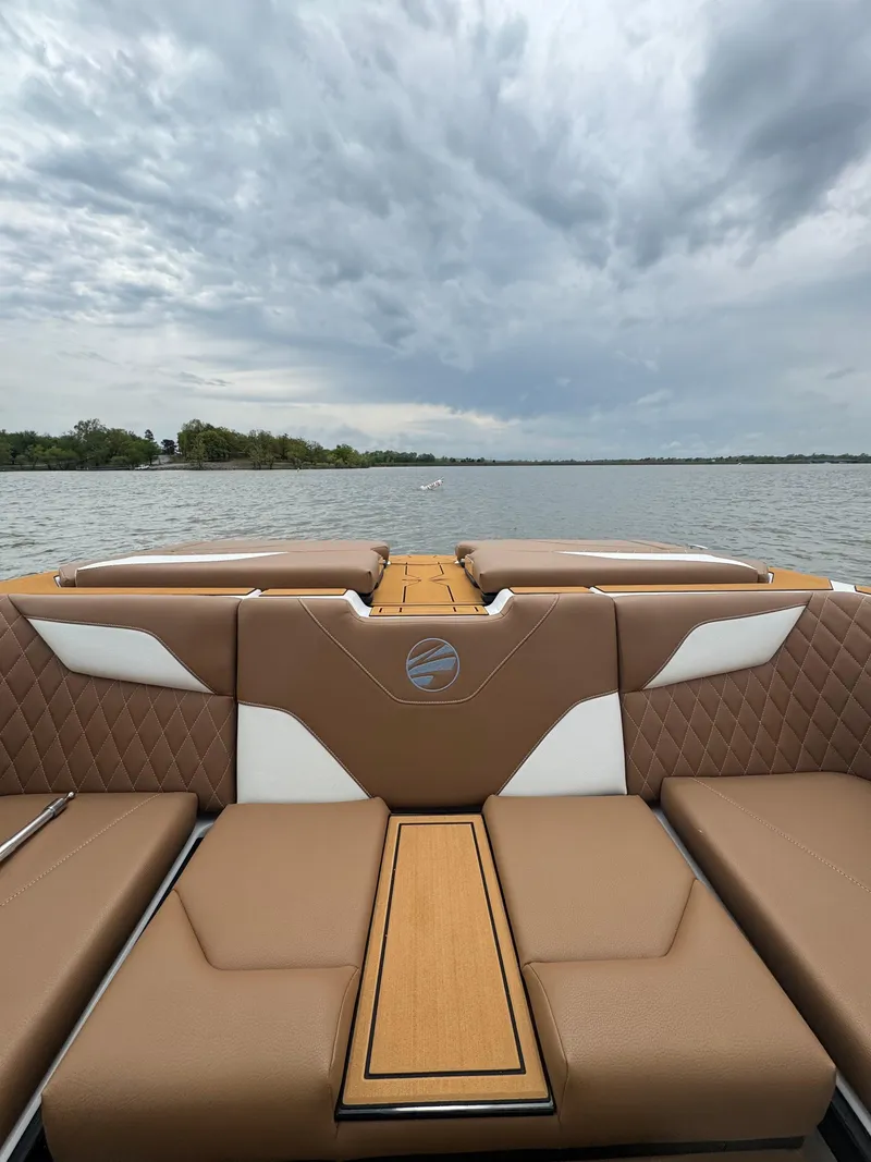 Slide: The Image of 2025 Tigé Z5 boat interior with brown and white seating, overlooking a calm lake. - 12