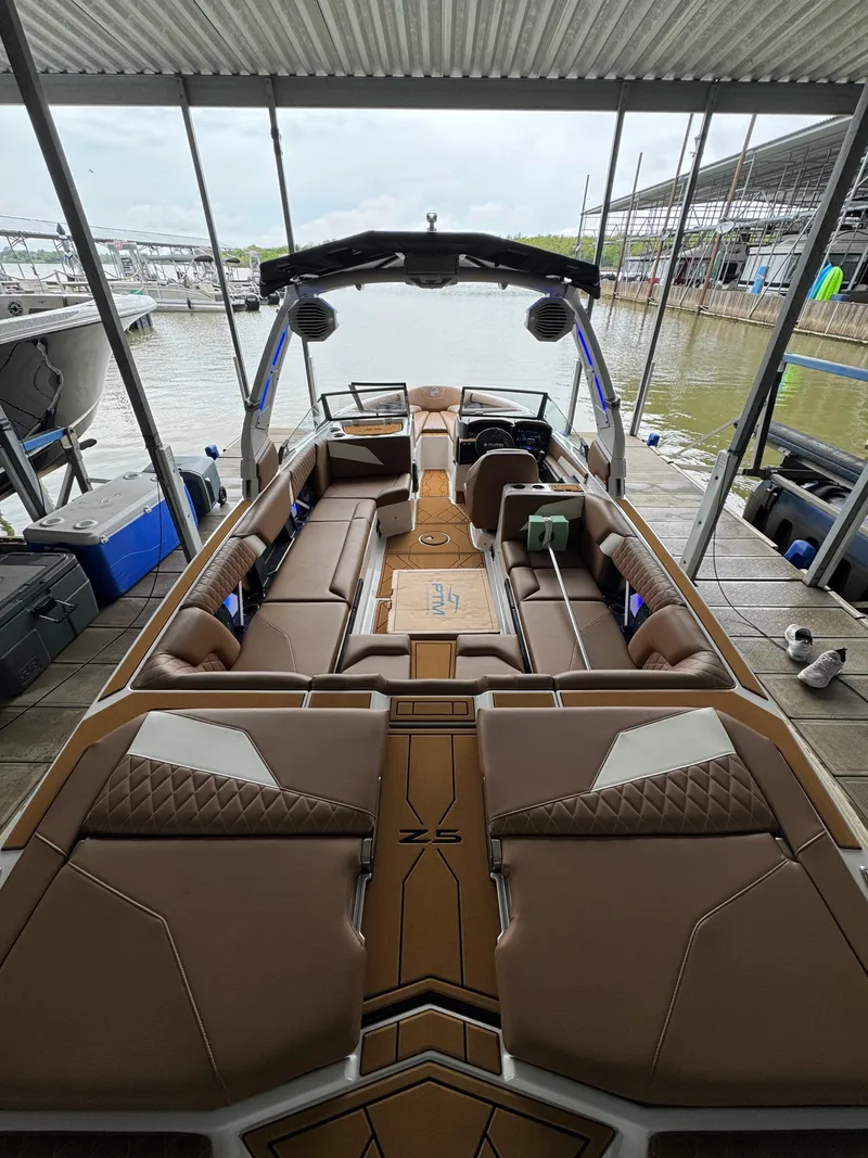 Slide: The Image of 2025 Tigé Z5 boat interior with luxurious brown seating, docked at a marina. - 17