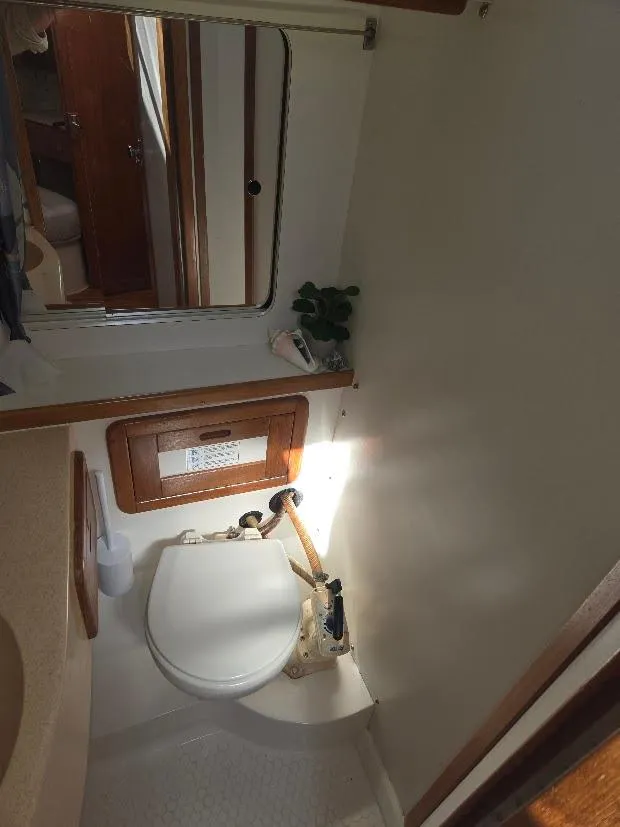 Slide: The Image of 1997 Catalina 42 MkII yacht bathroom with toilet, mirror, and wooden accents. - 44