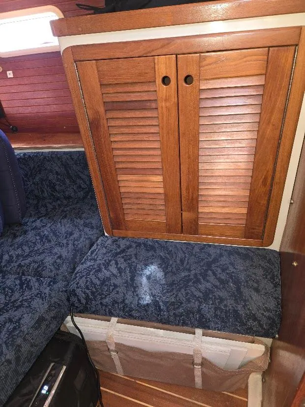 Slide: The Image of Interior of a 1997 Catalina 42 MkII sailboat with wooden cabinet and blue cushioned seating. - 49