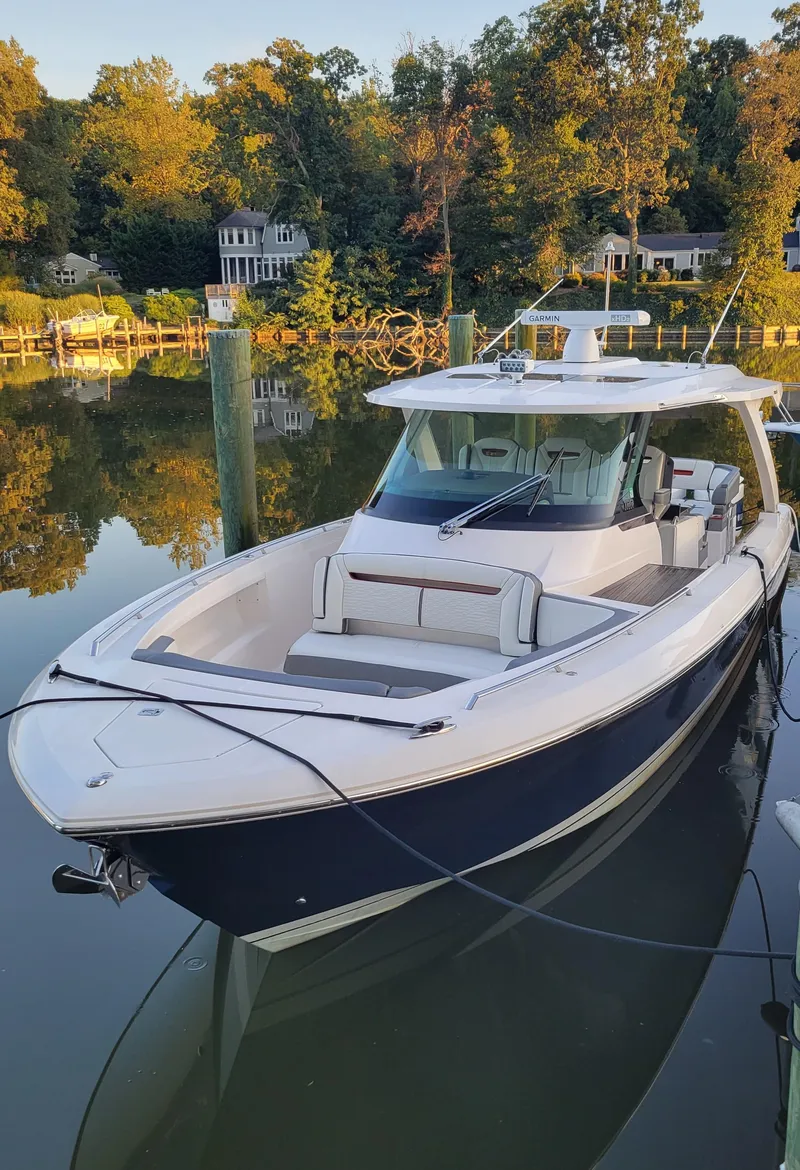 Slide: The Image of 2019 Tiara Sport 38 LS boat docked on calm water, surrounded by trees. - 0