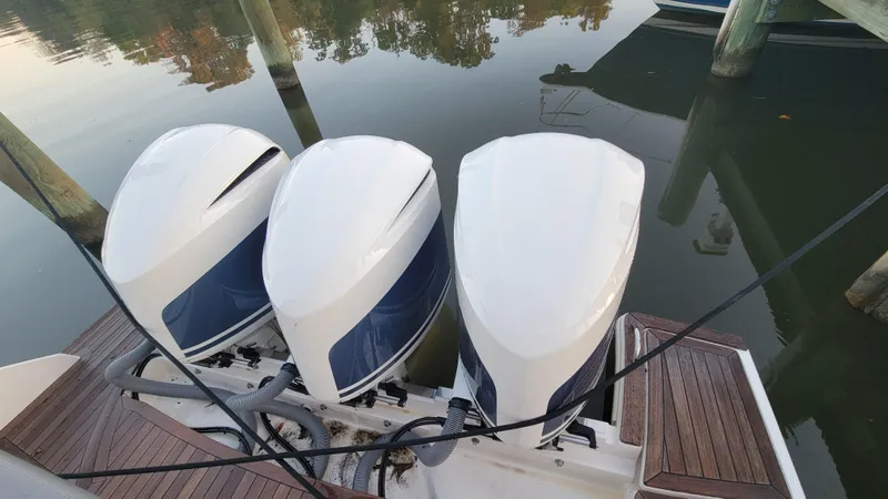 Slide: The Image of Three outboard motors on a 2019 Tiara Sport 38 LS boat, docked on calm water. - 15