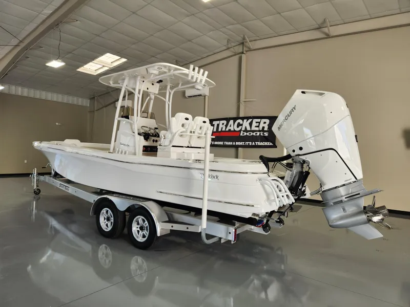 Slide: The Image of 2025 BlackJack 256 Coastal boat on trailer in showroom with Mercury outboard engine. - 2