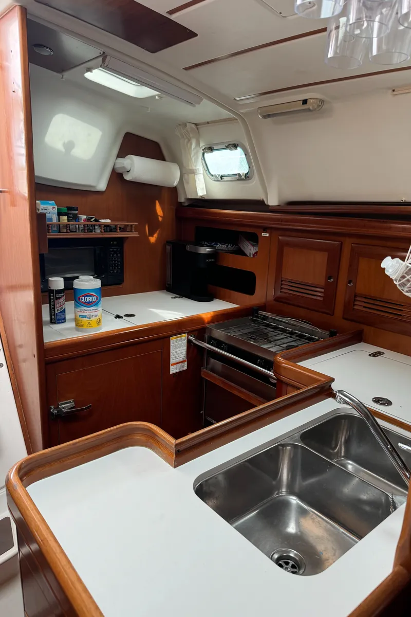 Slide: The Image of 2001 Beneteau 361 yacht kitchen with sink, stove, and wooden cabinetry. - 16