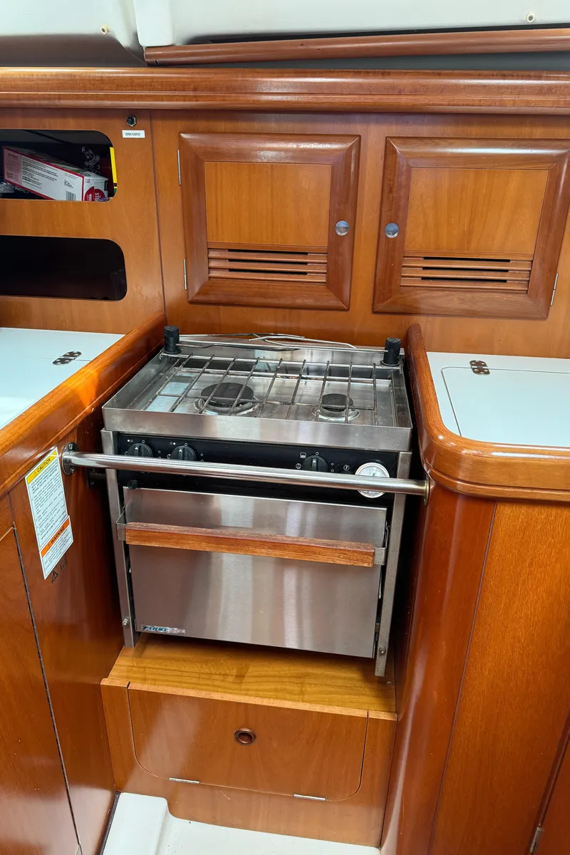 Slide: The Image of 2001 Beneteau 361 yacht kitchen with wooden cabinets and stainless steel stove. - 17