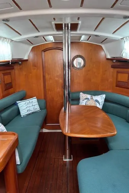 Slide: The Image of 2001 Beneteau 361 sailboat interior with wooden table, green seating, and nautical decor. - 27