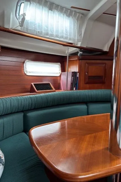 Slide: The Image of Interior of 2001 Beneteau 361 sailboat with wooden table and green seating. - 30