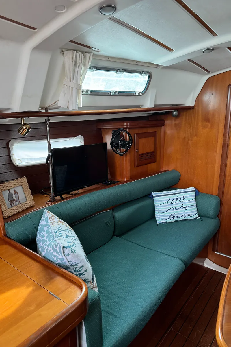 Slide: The Image of Interior of 2001 Beneteau 361 sailboat with green sofa, pillows, and wooden accents. - 36