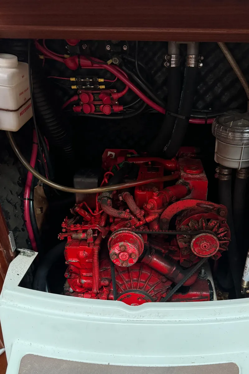 Slide: The Image of Engine compartment of a 2001 Beneteau 361 sailboat, featuring a red engine and wiring. - 44