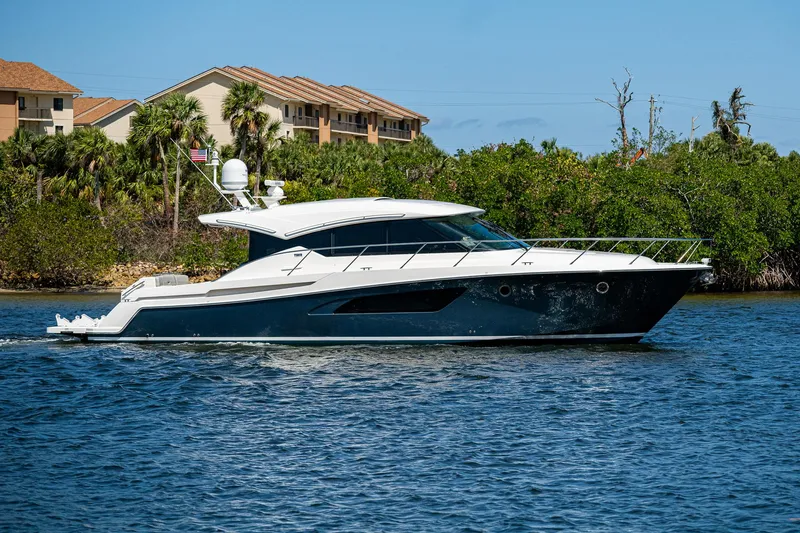 Slide: The Image of 2020 Tiara Yachts C53 Coupe cruising on a sunny day near lush greenery. - 0