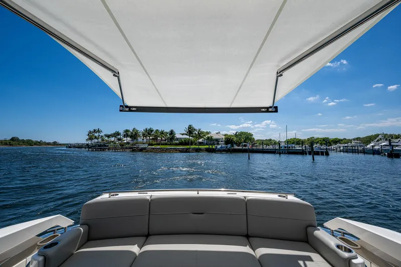 Slide: The Image of 2020 Tiara Yachts C53 Coupe, rear seating view, overlooking serene waterfront and blue sky. - 7