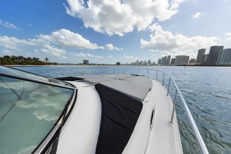 Slide: The Image of 2003 Sea Ray 380 Sundancer cruising on a sunny day with city skyline in background. - 26