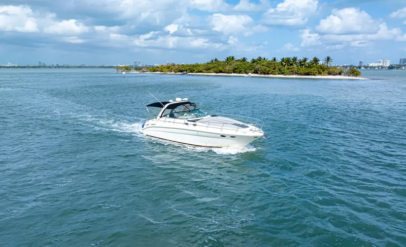 Slide: The Image of 2003 Sea Ray 380 Sundancer cruising near a tropical island under a partly cloudy sky. - 34