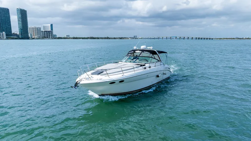 Slide: The Image of 2003 Sea Ray 380 Sundancer cruising on open water with city skyline in background. - 38