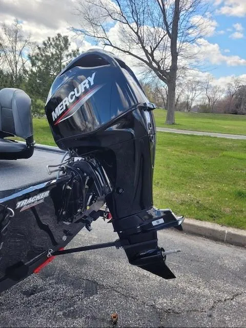 Slide: The Image of 2025 Tracker Bass Tracker Classic XL with Mercury outboard motor, parked on a paved area. - 2