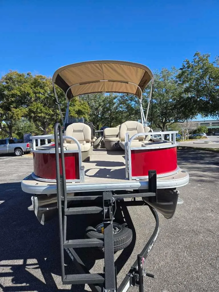 Slide: The Image of 2025 Sun Tracker Bass Buggy 18 DLX pontoon boat with canopy, parked outdoors. - 3