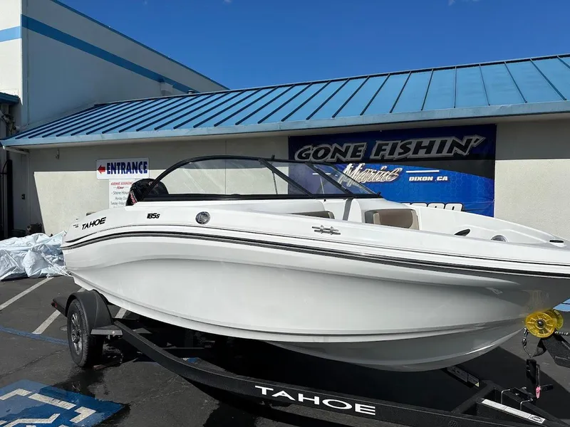 Slide: The Image of 2025 Tahoe 185 S boat on trailer, parked outside a building with blue roof. - 1
