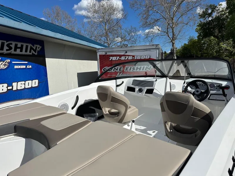 Slide: The Image of 2025 Tahoe 185 S boat interior with beige seating, parked near a building under a blue sky. - 3