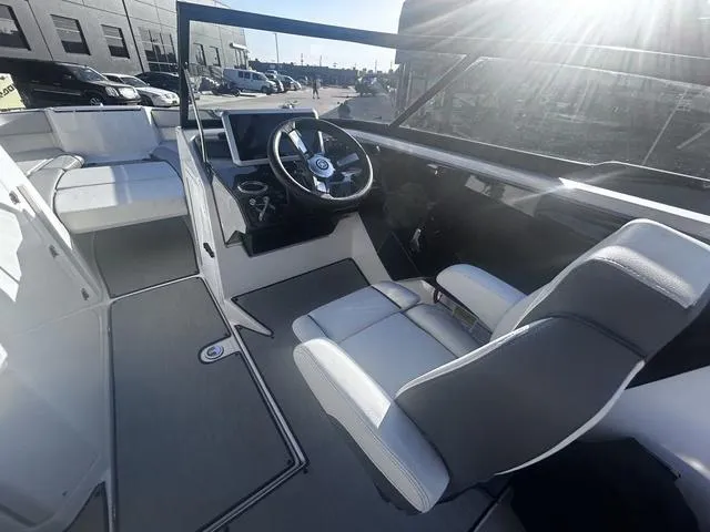 Slide: The Image of 2023 Yamaha Boats AR250 interior with steering wheel and seating, under bright sunlight. - 10