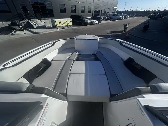 Slide: The Image of 2023 Yamaha Boats AR250 interior with spacious seating in a marina setting. - 12