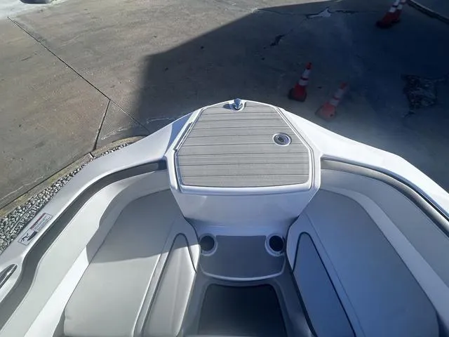 Slide: The Image of 2023 Yamaha Boats AR250 bow seating area with cup holders and deck view. - 13