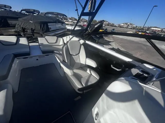 Slide: The Image of 2023 Yamaha Boats AR250 interior with sleek seating and modern design at a marina. - 16