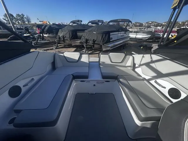 Slide: The Image of 2023 Yamaha Boats AR250 interior with sleek seating, docked among covered boats. - 17