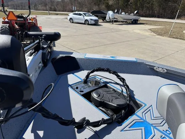 Slide: The Image of 2025 Xpress H20 boat deck with equipment, parked cars, and trees in the background. - 11