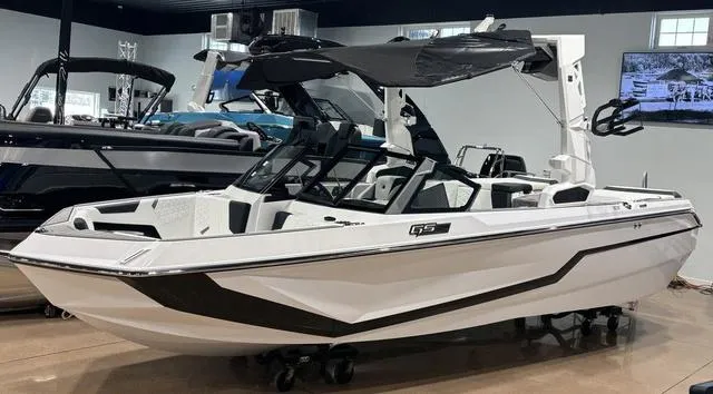 Slide: The Image of 2025 Nautique Super Air Nautique GS20 boat in showroom, sleek design, white and black accents. - 1