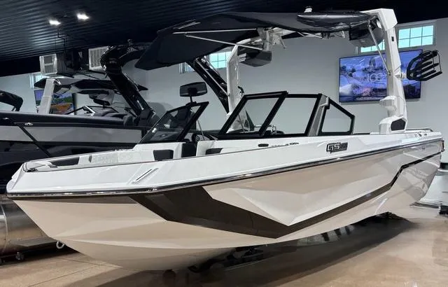 Slide: The Image of 2025 Nautique Super Air Nautique GS20 boat in showroom, sleek design, black and white color scheme. - 3