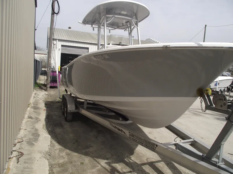 Slide: The Image of 2019 Sportsman Open 232 Center Console boat on trailer near a warehouse. - 2